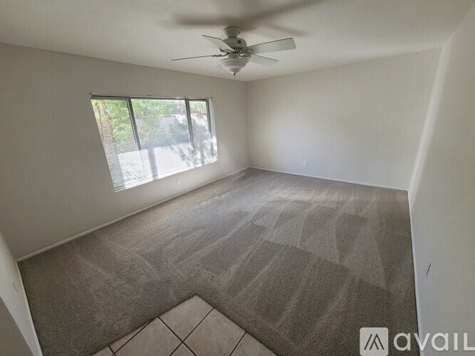A room with a ceiling fan and a window letting in natural light.