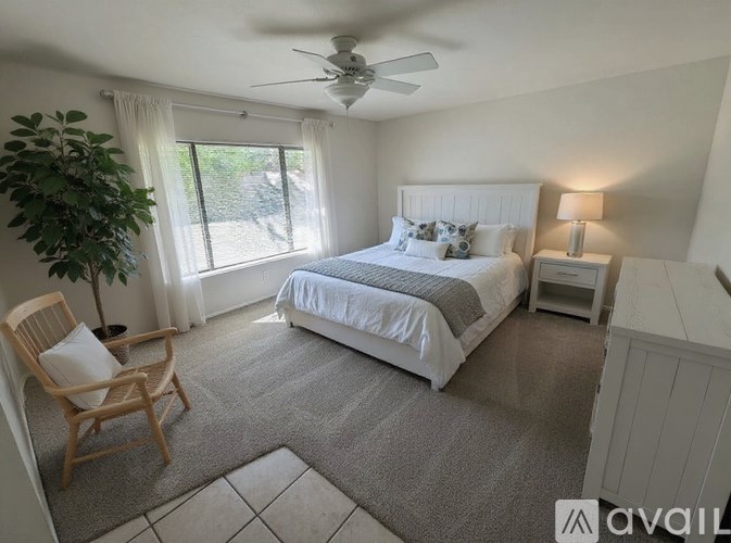 A bedroom with a large bed, a chair, and a ceiling fan.
