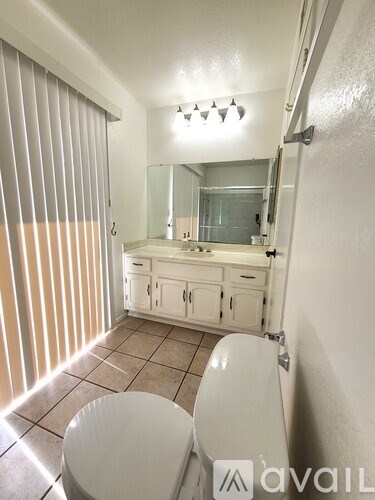 A bathroom with a toilet, sink, and mirror.