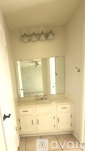 A bathroom with a sink, mirror, and cabinets.