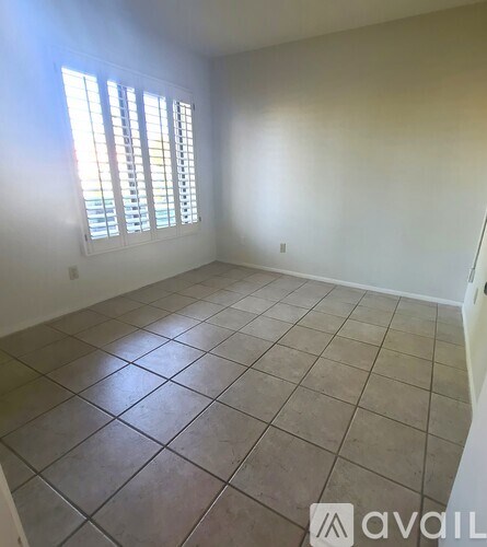 A room with tiled flooring and a window with blinds.