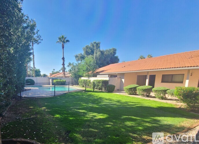 A sunny day at a house with a pool and a fence.