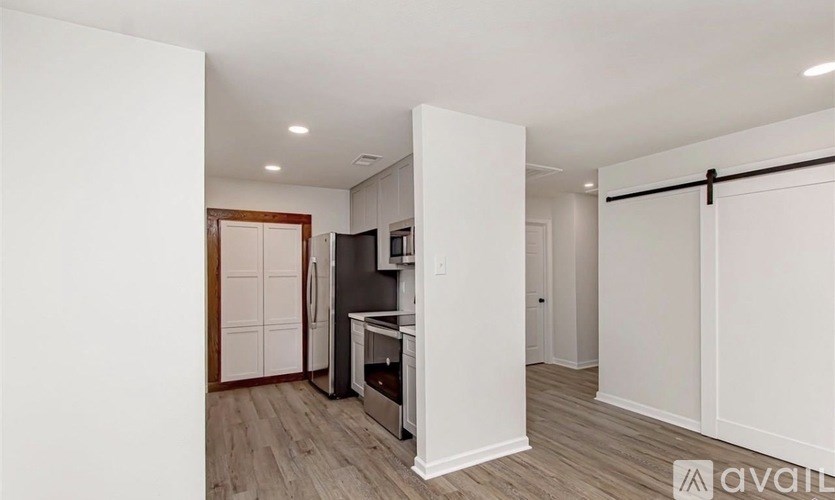 A kitchen with white cabinets and a wooden door.