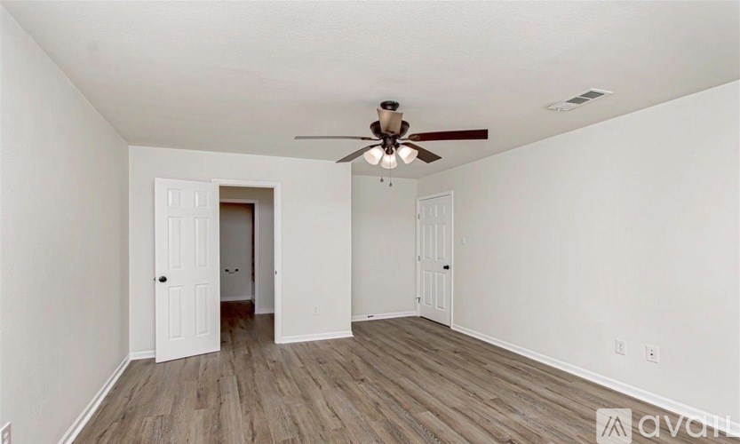 A room with a ceiling fan and wooden flooring.