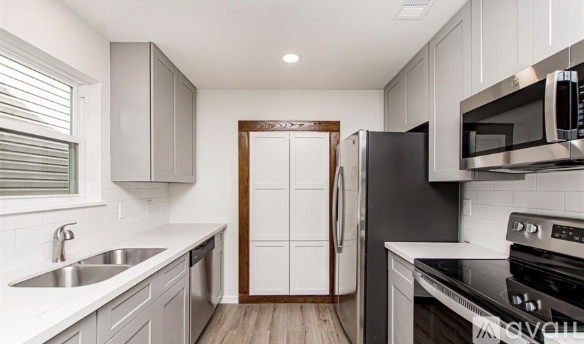 A kitchen with a black fridge and stove top oven.
