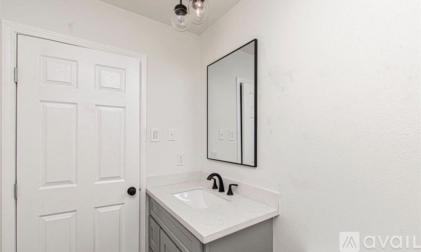 A bathroom with a white sink and a white door.