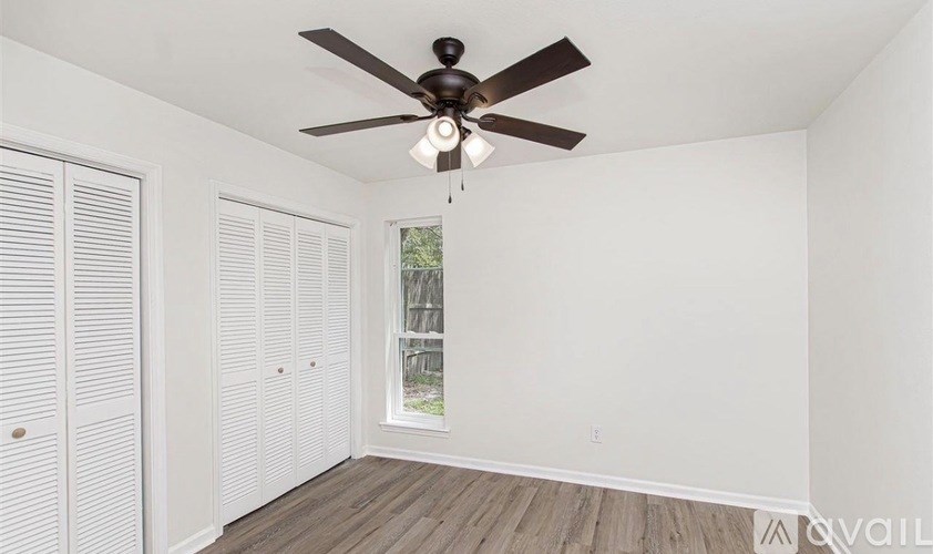 A room with a ceiling fan and a window with white blinds.