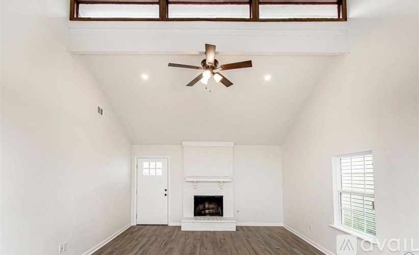 A living room with a fireplace and a ceiling fan.