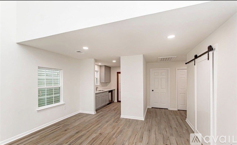 A spacious room with wooden flooring and white walls.