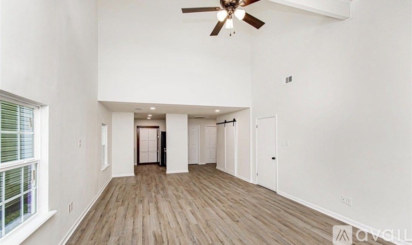 A spacious room with a ceiling fan and wooden flooring.