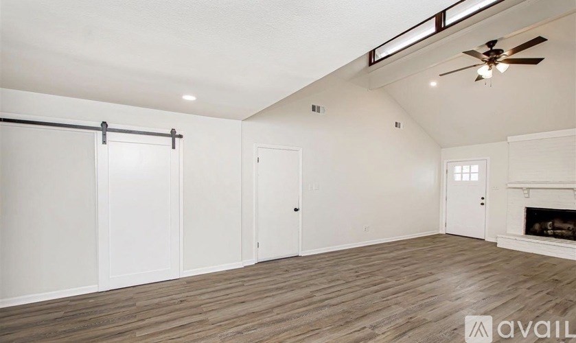 A spacious room with a fireplace and a ceiling fan.