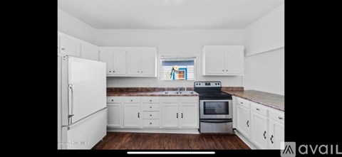 A kitchen with white cabinets and a wooden floor.