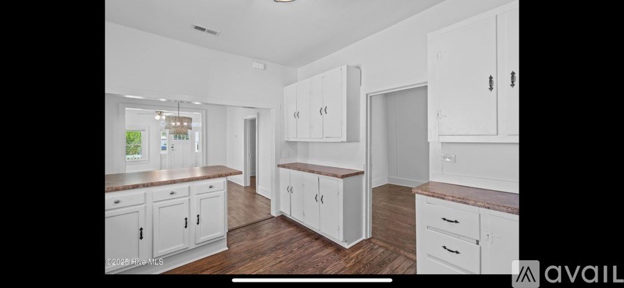 A kitchen with white cabinets and a wooden floor.