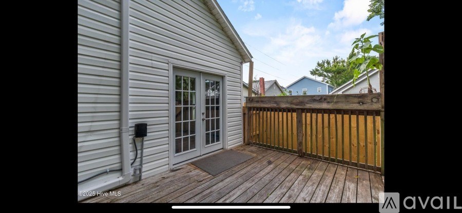 A wooden deck with a white house and a wooden fence.