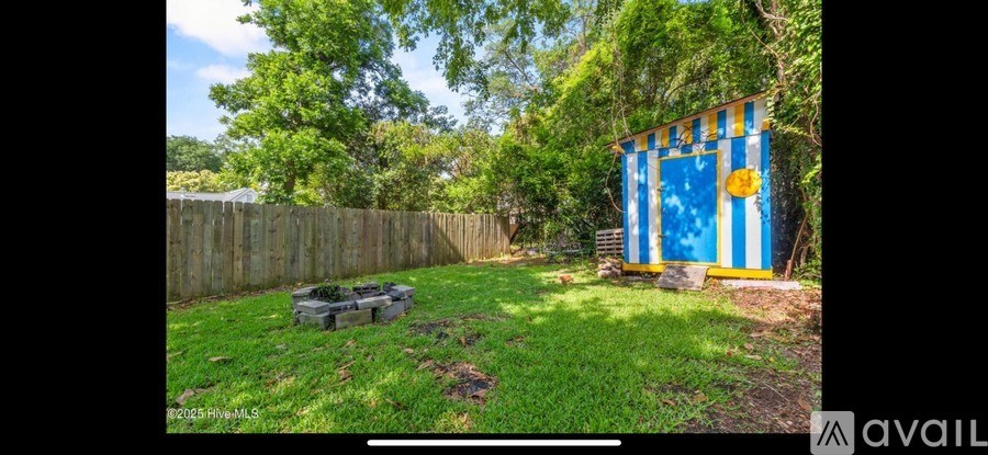 A blue and yellow shed sits in a backyard with a wooden fence and green grass.