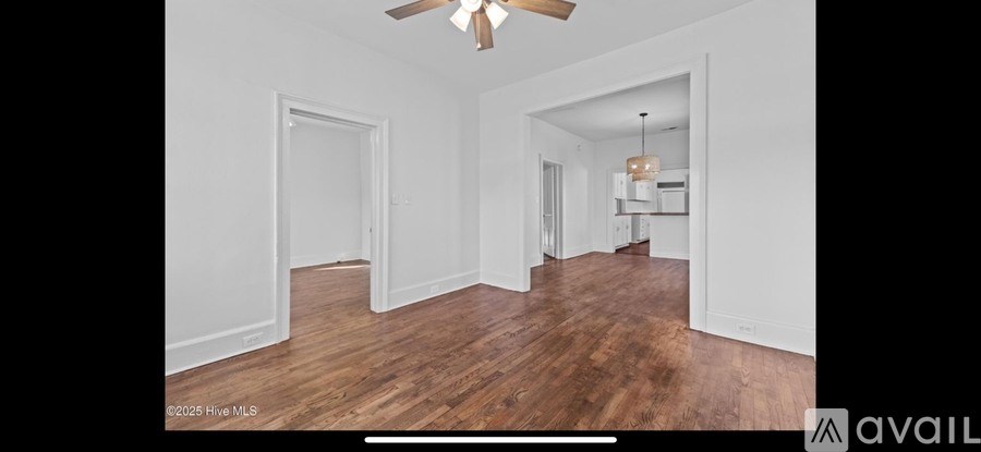 A spacious room with wood flooring and a ceiling fan.