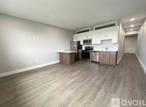 A spacious kitchen with wooden flooring and white walls.