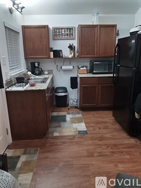 A kitchen with wooden cabinets and a black refrigerator.