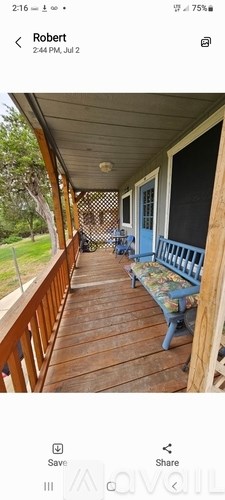 A wooden porch with a blue bench and a white door.