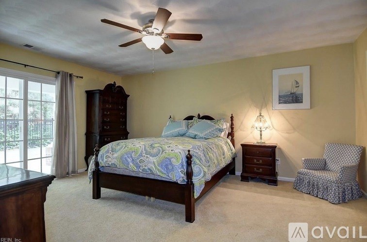 A bedroom with a bed, chair, and a ceiling fan.