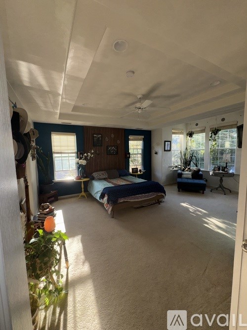 A bedroom with a bed, a desk, and a ceiling fan.