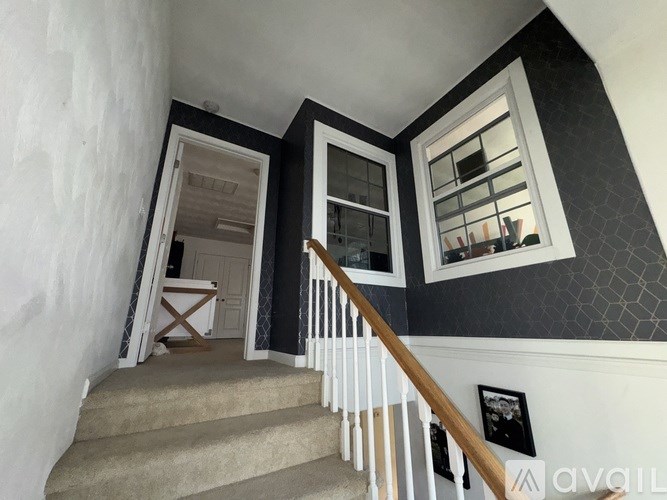 A staircase with a beige carpet and a wooden handrail.
