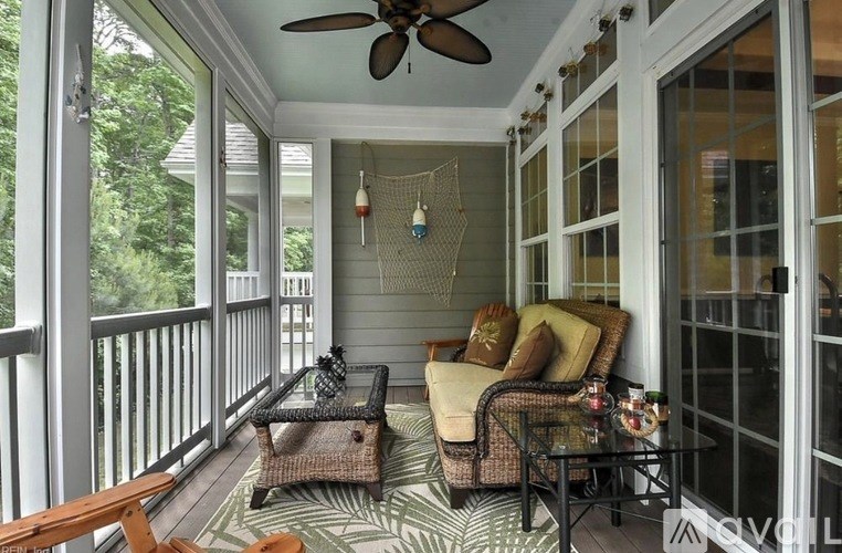 A patio with a wicker chair and a table with a glass top.