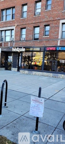 A sign is posted on the sidewalk in front of a building.