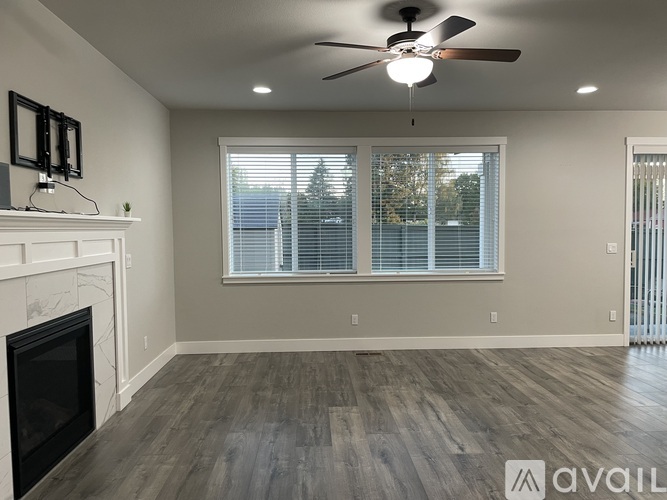A living room with a fireplace and a ceiling fan.