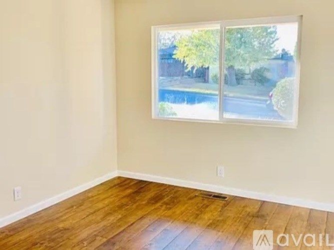 A room with a wooden floor and a window showing a street view.