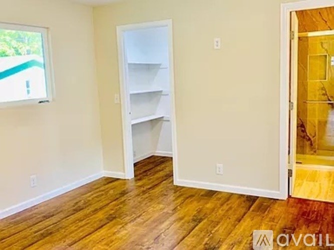 A room with a white shelving unit and wooden floors.