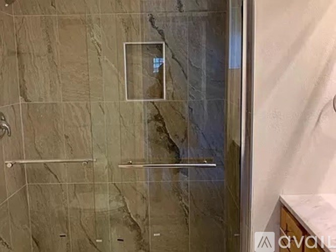 A bathroom with a marble wall and a glass shower door.