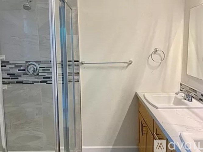 A bathroom with a white sink and a glass shower door.
