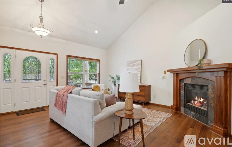 A living room with a grey couch, a fireplace, and a chandelier.