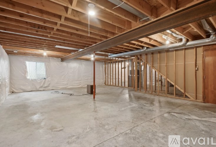 A spacious, unfinished room with wooden beams and a concrete floor.
