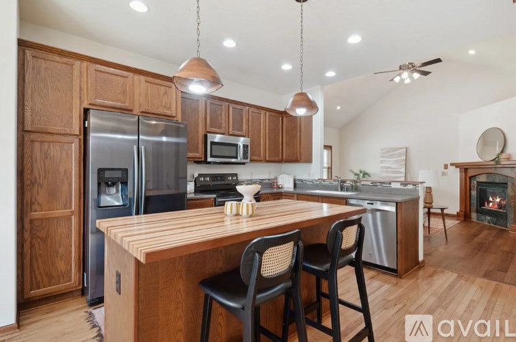 A kitchen with wooden cabinets and a wooden island with chairs.