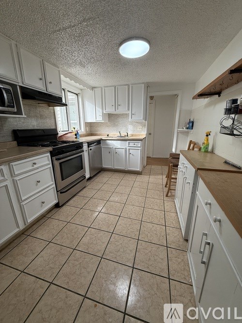A kitchen with white cabinets and a tiled floor.