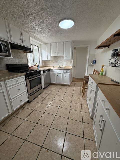 A kitchen with white cabinets and a tiled floor.