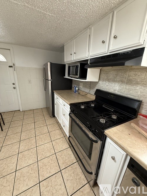 A kitchen with black appliances and white cabinets.