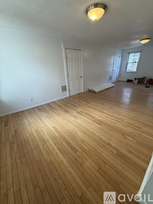 A room with wooden flooring and a white door.