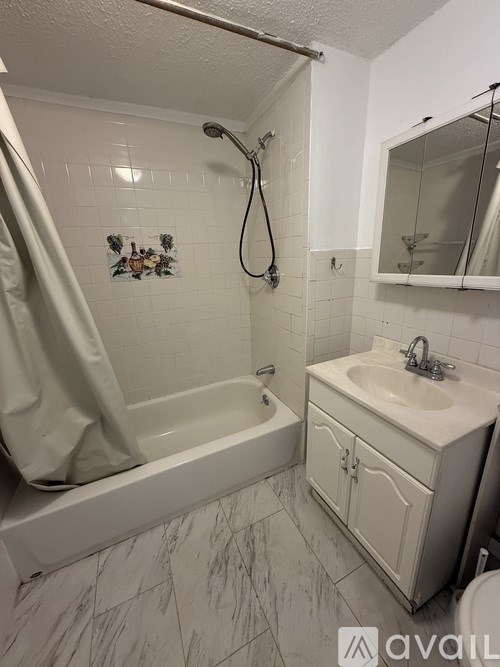 A bathroom with a white tub, sink, and marble floor.