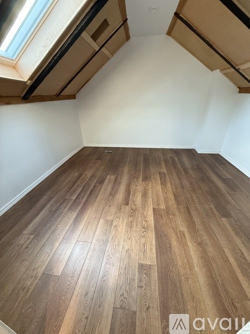 A room with wooden flooring and a skylight.
