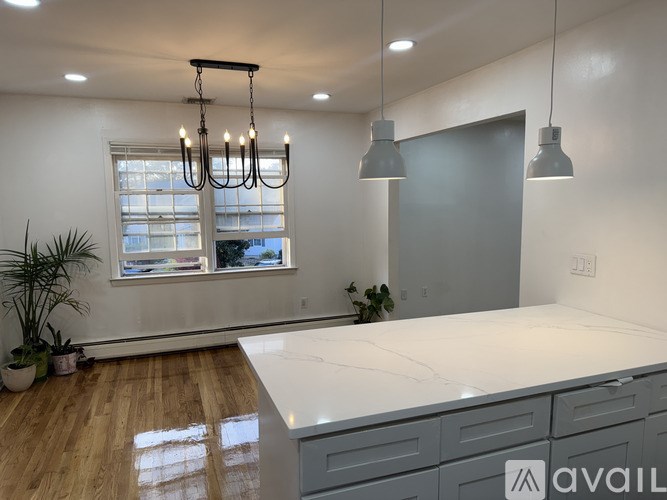 A modern kitchen with a large island and pendant lights.