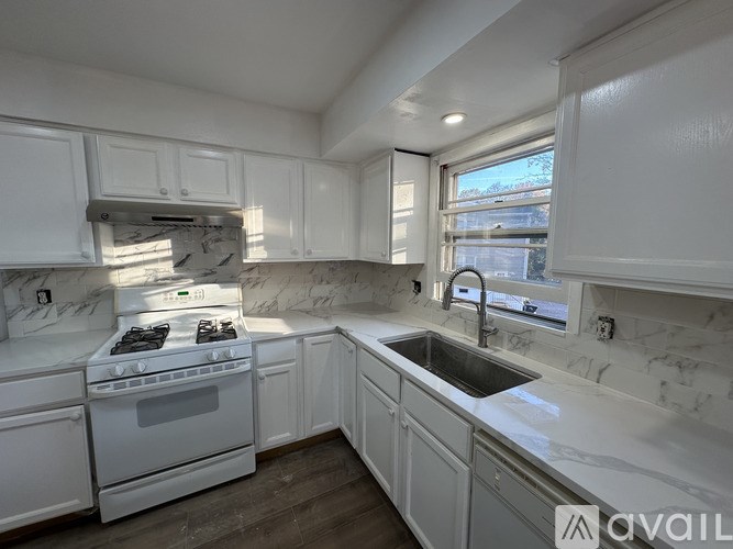 A kitchen with white cabinets and a marble countertop.