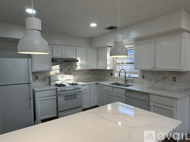 A kitchen with white appliances and marble countertops.
