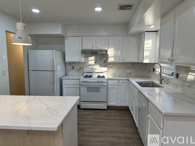 A kitchen with white cabinets and a marble countertop.