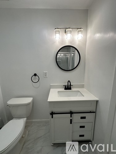 A white bathroom with a toilet, sink and mirror.
