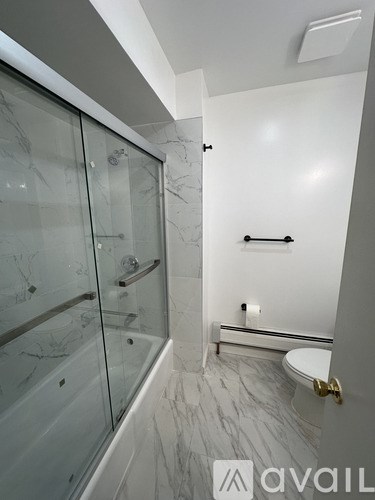 A bathroom with a glass shower stall and a toilet.