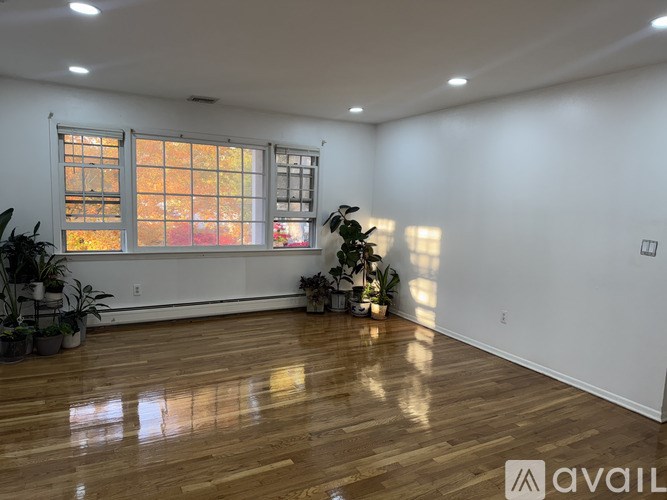 A room with wooden floors and a large window letting in sunlight.
