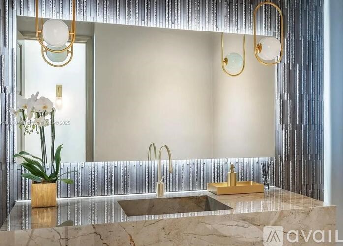 A bathroom with a marble countertop and two gold-framed mirrors.